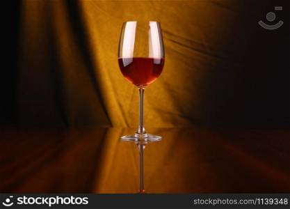 Glass of rose wine over a draped background lit yellow