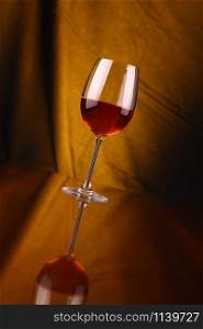 Glass of rose wine over a draped background lit yellow