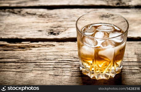 glass of rum and ice. On wooden background.. glass of rum and ice.