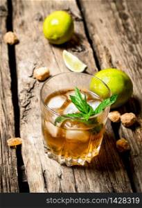 glass of rum with ice , lime and mint. On wooden background. glass of rum with ice , lime and mint.