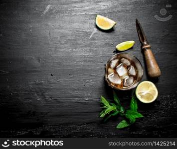 glass of rum with lime and mint. On a black wooden background.. glass of rum with lime and mint.