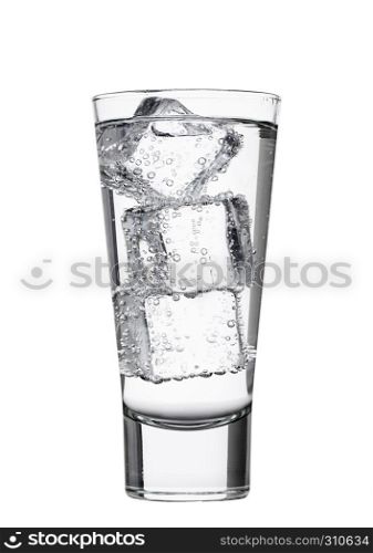 Glass of sparkling mineral water with ice cubes on white background