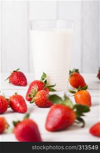 Glass of strawberry fresh milk on wooden background with fresh strawberries