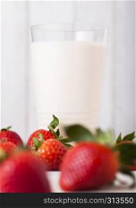 Glass of strawberry fresh milk on wooden background with fresh strawberries