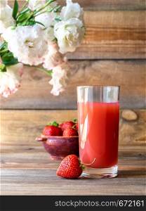 Glass of strawberry juice with fresh strawberries on the wooden background