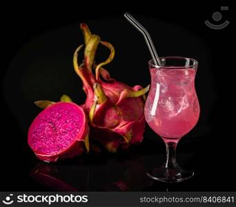 Glass of tasty pitahaya cocktail and fresh dragon fruits on dark background. Glass of tasty pitahaya cocktail