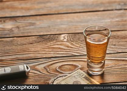 Glass of tequila or alcohol drink and car key. Drink and drive concept. . Glass of tequila or alcohol drink and car key on rustic wooden table with copy-space. Drink and drive and alcoholism concept. Safe and responsible driving concept.
