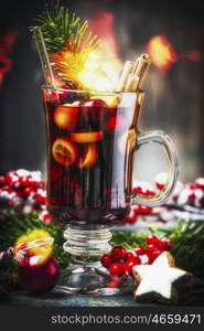 Glass of traditional mulled wine or punch with Christmas decoration , fir branches and festive bokeh lighting