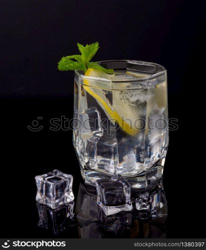 Glass of vodka with ice on a black background. Vodka with lemon and ice on a black background
