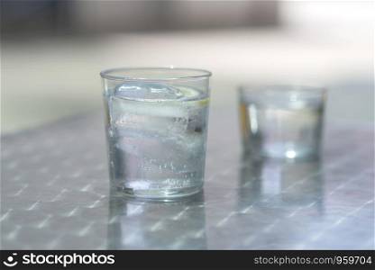 Glass of water with ice on a metallic table outdoors in a bright day