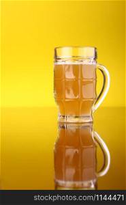 Glass of wheat beer over a brigth yellow background