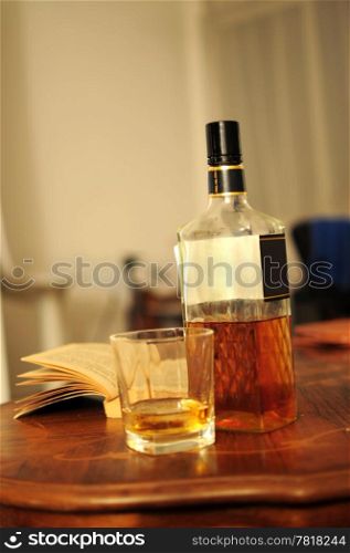 Glass of whiskey, bottle and opened book on home table