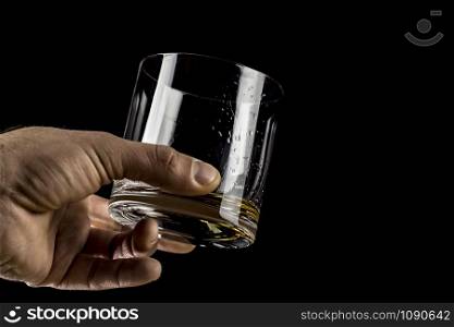 glass of whiskey in hand on a black background