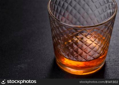 Glass of whiskey on a black stone table. Top view with copy space. A glass of whiskey or cognac on a black concrete table. Relaxation time
