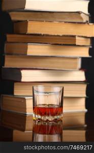 Glass of whiskey on a reflective surface with books