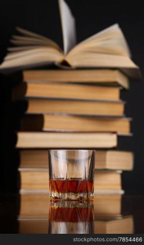 Glass of whiskey on a reflective surface with books