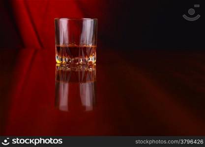 Glass of whiskey over a draped background lit yellow