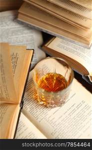 Glass of whiskey standing on several open books