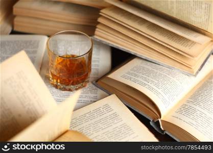Glass of whiskey standing on several open books