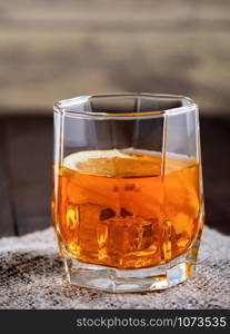 Glass of whiskey with ice and lemon on canvas. Glass of whiskey with ice on rustic background
