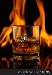 Glass of whiskey with ice on a background of fire