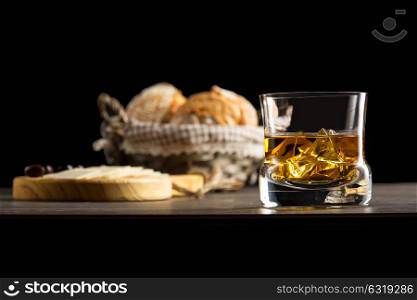 glass of whisky in a dark ambient with appetizers brad and cheese