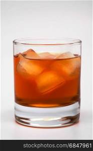 Glass of whisky with an ice on a grey background