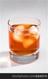 Glass of whisky with an ice on a grey background