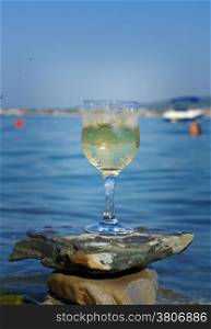 Glass of white wine by the coast.on the rocks, washed by the waves of the sea