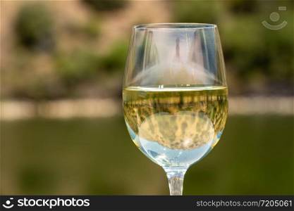 Glass of white wine for tasting on deck of cruise boat on the river in the Douro valley in Portugal. Glass of white wine on a cruise boat on Douro river in Portugal