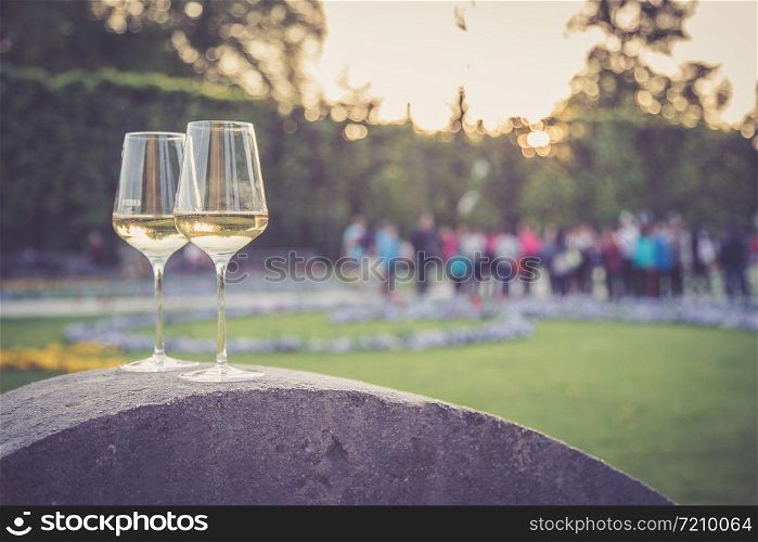 Glass of white wine on a stone wall in the formal garden. Enjoying it in the own garden in the evening sun.