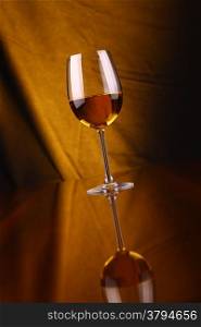 Glass of white wine over a draped background lit yellow