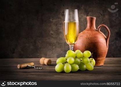 Glass of white wine, pitcher and grapes on grunge background