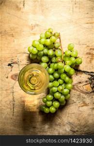 glass of white wine with a branch of ripe grapes. On wooden background.. glass white wine with a branch ripe grapes.