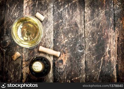 glass of white wine with a corkscrew. On a wooden background.. glass of white wine with a corkscrew.