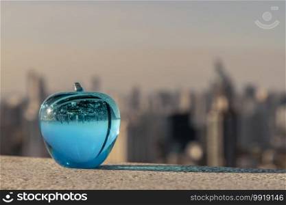 Glass or Crystal blue apple and reflective surface on cityscape background. Copy space, No focus, specifically.