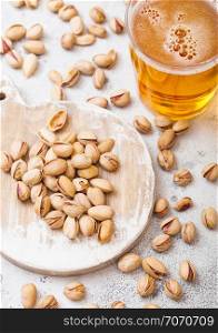 Glass pint of craft lager beer with pistachio nuts on stone kitchen background. Beer and snack.