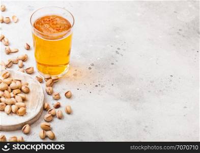 Glass pint of craft lager beer with pistachio nuts on stone kitchen background. Beer and snack.