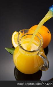 glass pitcher and orange juice on black background