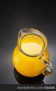 glass pitcher and orange juice on black background