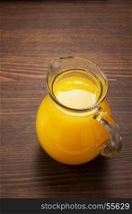 glass pitcher and orange juice on wooden background