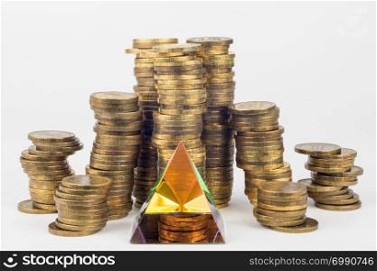 Glass pyramid in the foreground, in the background large stacks of coins