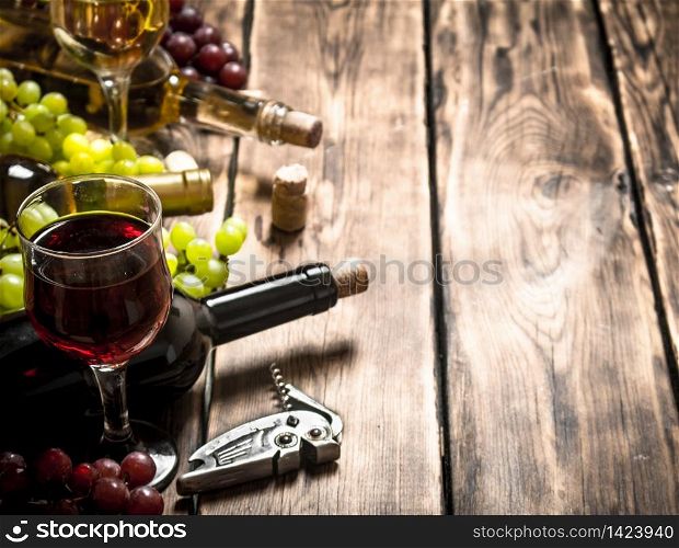 glass red wine with branches of white and red grapes. On a wooden table.. Fresh red and white wine