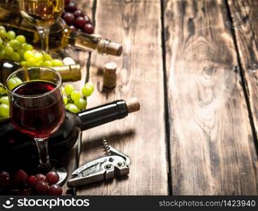 glass red wine with branches of white and red grapes. On a wooden table.. Fresh red and white wine