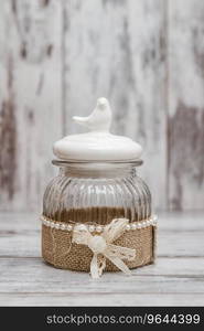 Glass round jars with linens, ribbons and birds on white wooden background