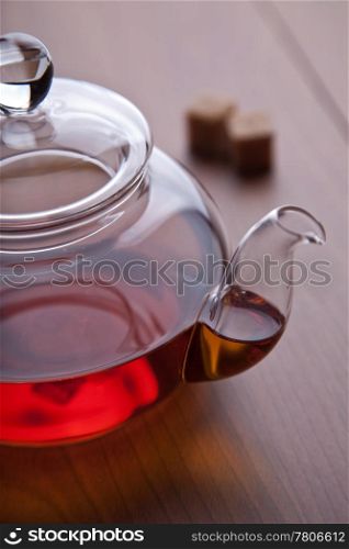 glass teapot with black tea and sugar cubes