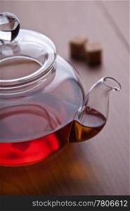 glass teapot with black tea and sugar cubes