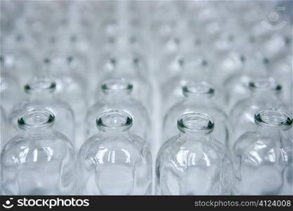 Glass transparent empty bottles in rows, cosmetics assembly line
