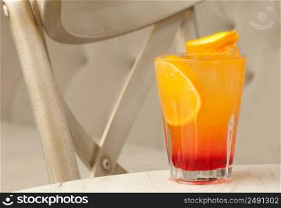 glass transparent glass with juice and lemon on the table against the background of the chair and sofa. a glass with a drink on the table