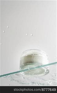 Glass tube of cosmetic product with cream on a glass shelf and water drops on a white background, bottom view. Skin care concept. Glass tube of cosmetic